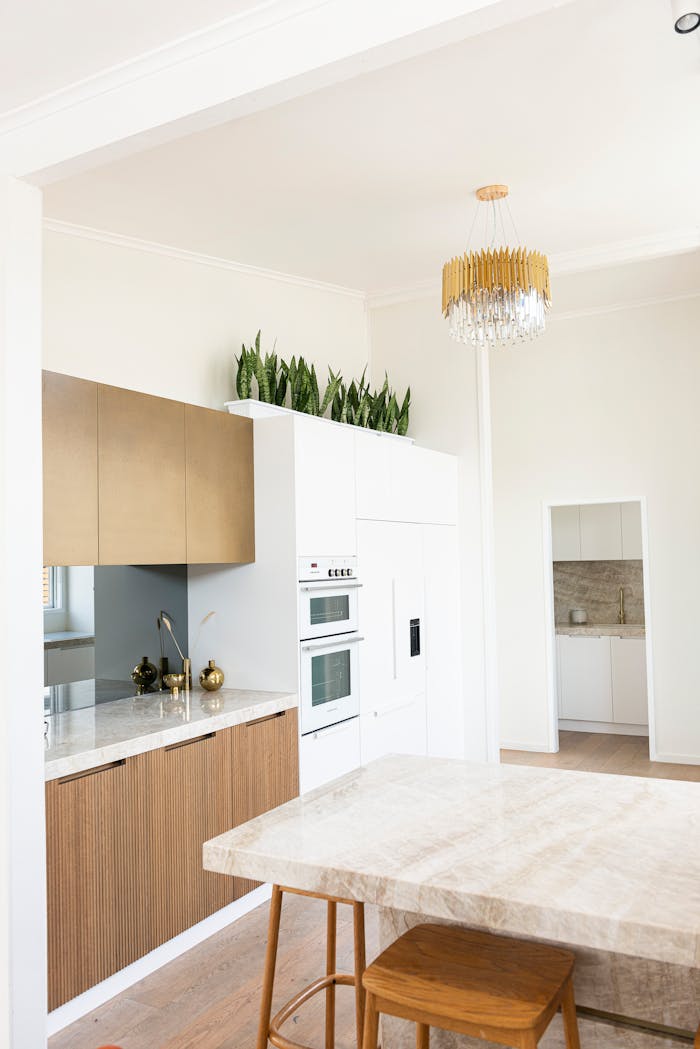creative-01 Bright minimalist kitchen interior featuring marble countertops and a chandelier.