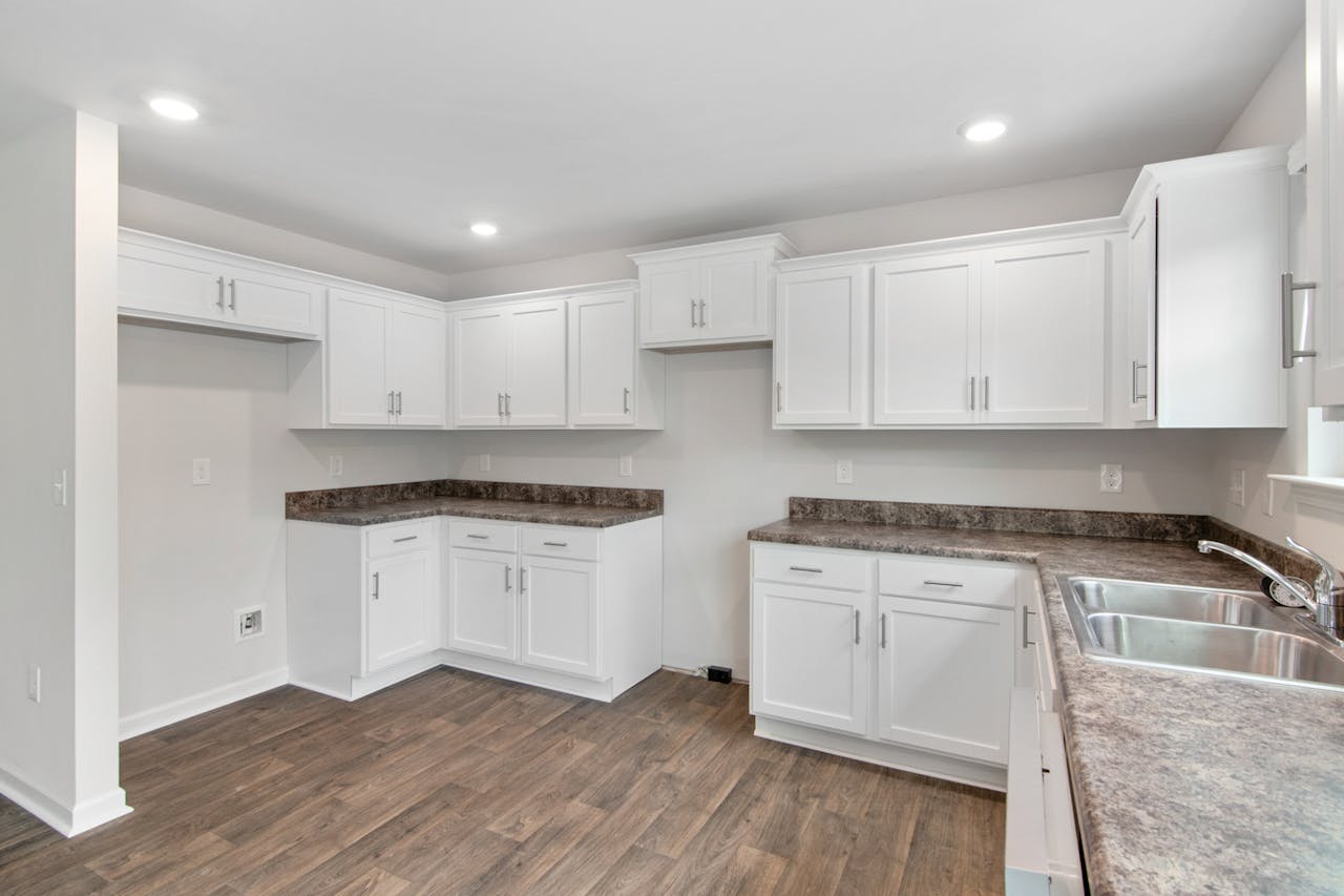 creative-02 Spacious modern kitchen featuring white cabinetry, wooden floors, and natural lighting. Ideal for contemporary homes.