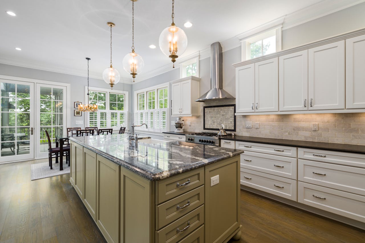 creative-03 Bright and spacious kitchen with white cabinetry, granite island, pendant lights, and natural light.