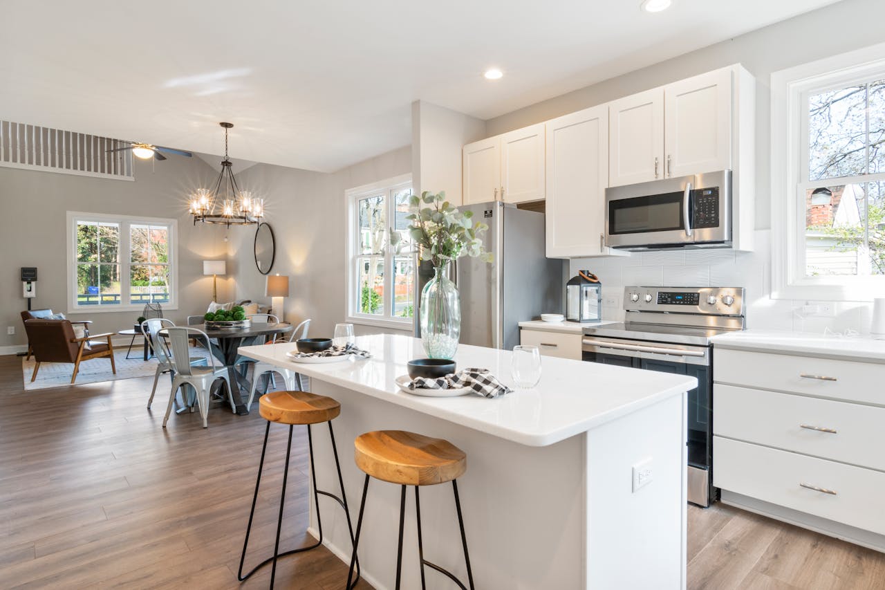 creative-03 Spacious kitchen with white cabinets, island, and dining area featuring chandeliers.