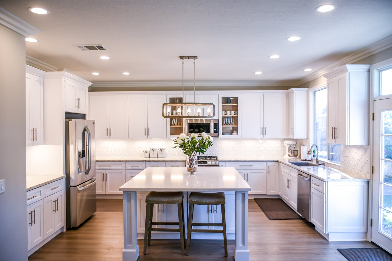 mobile-02 Spacious and elegant kitchen featuring white cabinetry, island, and stainless steel appliances.